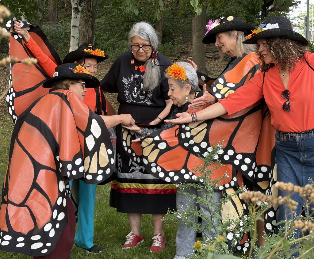 Elder and people releasing monark butterflies , dressed as Monarks